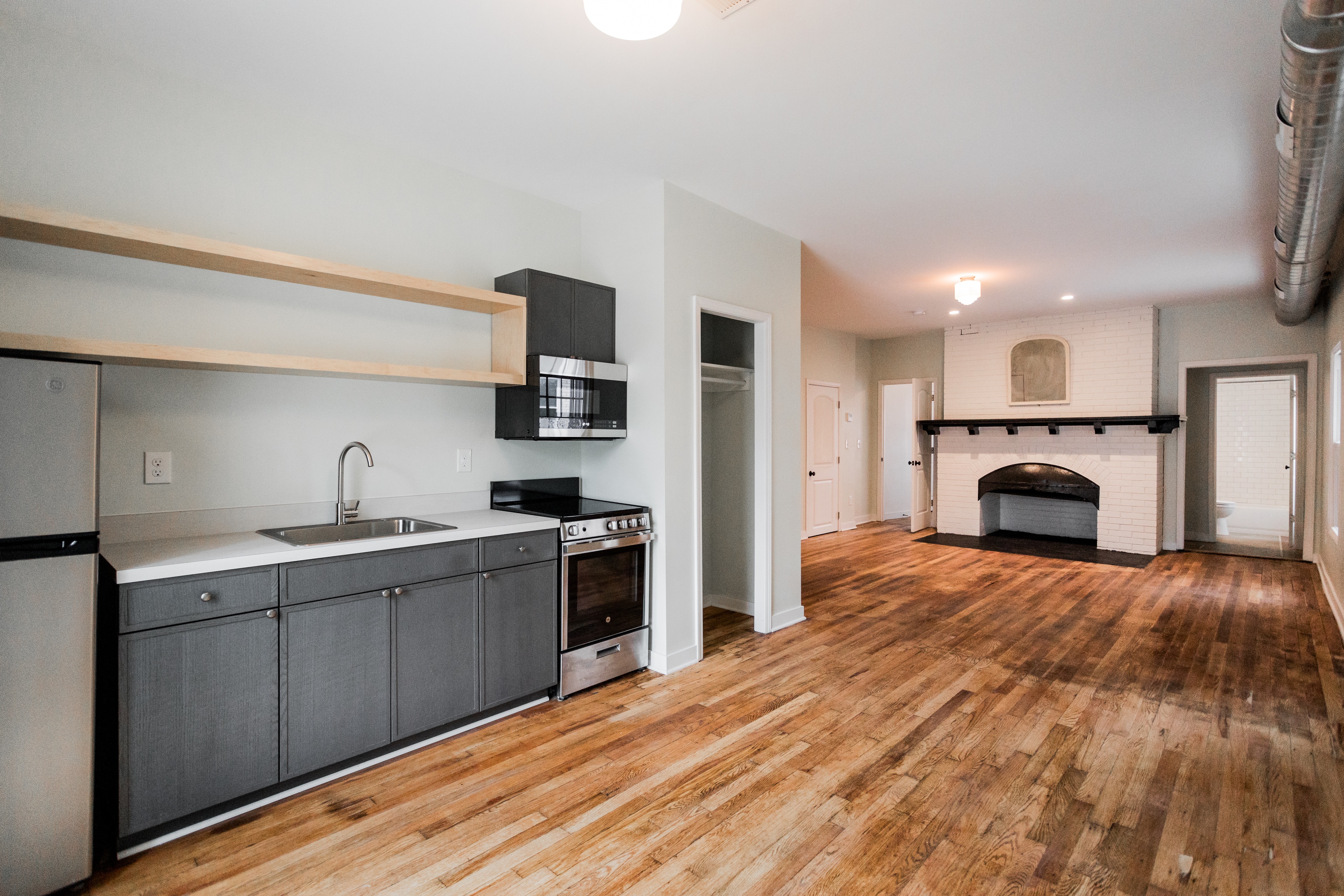 A kitchen with wooden floors and a stove top oven.